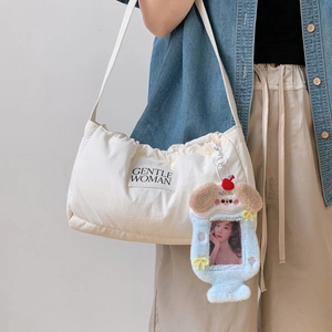 Blue plush cartoon photocard holder charm displayed on a white branded canvas bag