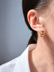 Close-up of a twisted gold hoop earring worn by a model in a stylish fashion setting