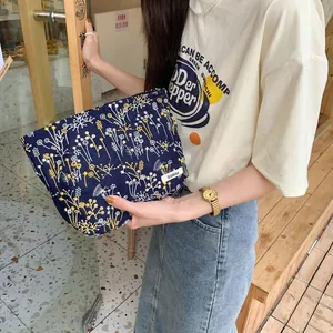 Detail of navy blue floral makeup bag with delicate white and yellow flower embroidery