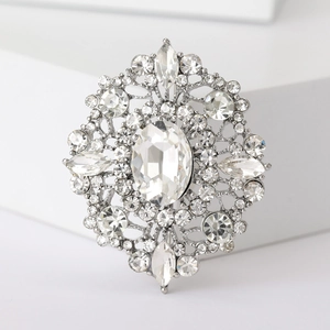 Macro detail of vintage silver oval brooch featuring clear crystals and intricate patterns