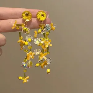 Detailed macro of flower drop earrings with yellow resin beads and crystals