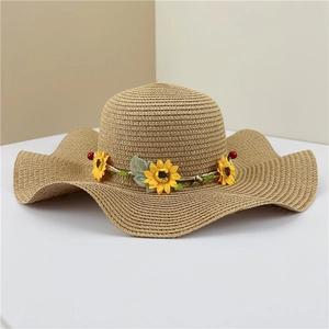 Detail of woven straw sun hat featuring a wavy brim and yellow sunflower floral band