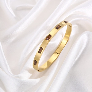 Luxurious gold titanium steel bangle with five rectangular brown zircon stones on white silk