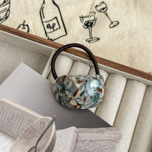 Close-up of marble pattern resin accessory on high elasticity black hair tie in a jewelry box