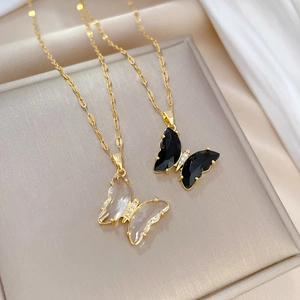 Macro view of crystal butterfly pendants in black and white on golden wave chains