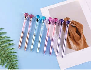Macro view of crystal ballpoint pens with large diamond tops and shimmering sand fill