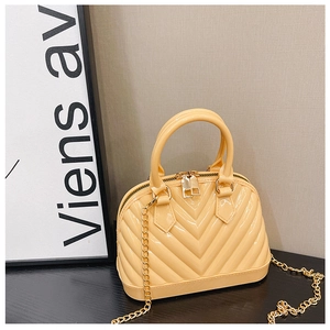 Detail of yellow PVC jelly bag with V-quilted pattern and gold chain strap