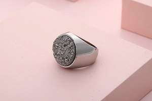 Macro shot of silver stainless steel ring with grey druzy stone on a pink geometric base