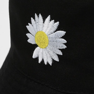 Black cotton bucket hat featuring detailed white daisy embroidery with yellow center
