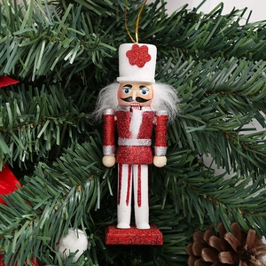 Close-up of a red glitter nutcracker soldier ornament hanging on a Christmas tree branch