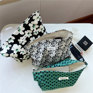 Three assorted canvas makeup pouches with floral and geometric prints and metal zippers
