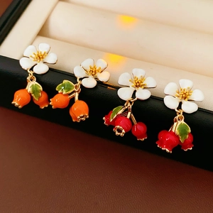 Detail of vintage flower and berry earrings with colorful drip oil glaze on stands