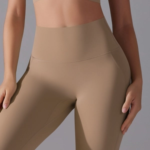 Detail view of high-waisted camel yoga leggings with ergonomic stitching and matte texture