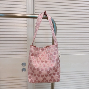 Detail of pink heart-patterned jacquard tote bag with soft fabric texture and side label