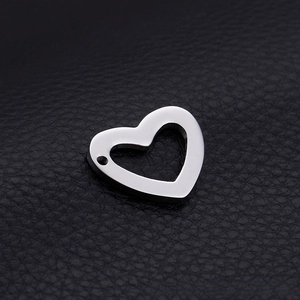Macro shot of silver stainless steel hollow heart pendant on black leather background