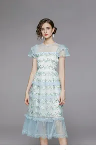 Détail de broderie de fleurs bleues et jaunes sur une robe à volants en tulle bleu