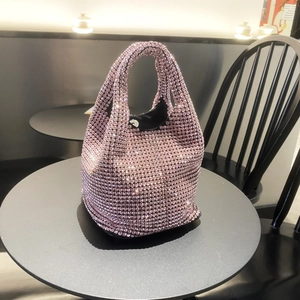 Detail shot of a pink rhinestone bucket bag with sparkling crystals on a cafe table