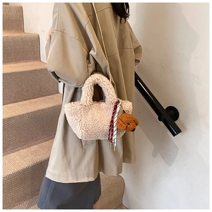 Detail of plush cream bucket bag with detachable strap and teddy bear charm on stairs