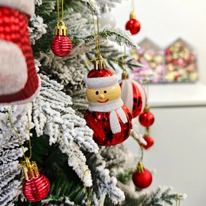 Gros plan d'un ornement de bonhomme de neige et de boules rouges sur un sapin de Noël