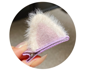 Detailed view of plush cat ear hair clip with white and pink faux fur and purple base