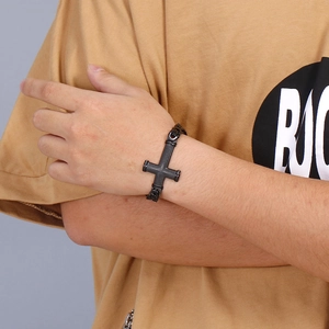 Detail of men's black stainless steel cross chain bracelet worn on a wrist