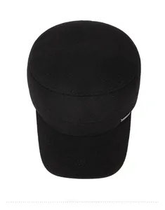 Detail view of black flat top cap with cross metal emblem and thick twill texture