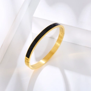 Detail view of gold stainless steel bangle with black enamel inlay and side clasp closure