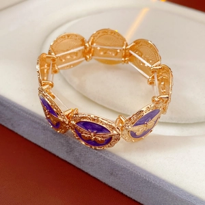 Detailed close-up of vintage gold bee bracelet with purple enamel on a velvet display