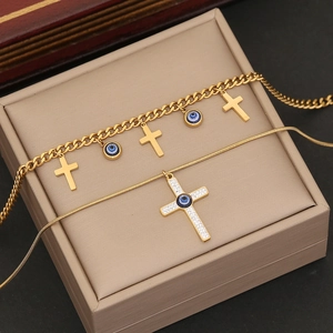 Detail of gold evil eye and cross pendants on snake and cuban link chain jewelry