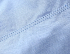 Detailed macro view of light blue woven fabric with high-quality double-needle stitching