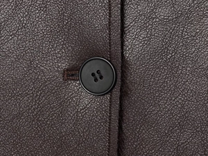 Macro shot of dark brown faux leather texture with stitching and black button detail