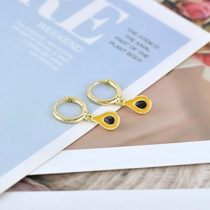 Detailed macro view of gold-plated hoop earrings with creative black and yellow drop charms