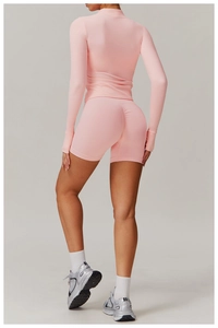Detail view of pink slim-fit yoga jacket with thumb holes and high-waist scrunch shorts