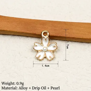 Detail view of flower pendant with white enamel petals, gold edges, and a pearl center