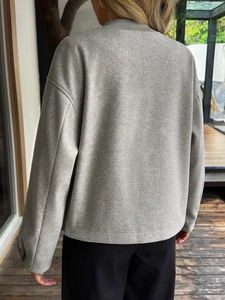 Vista posteriore dettagliata di un cardigan in lana a maglia grigio chiaro da donna
