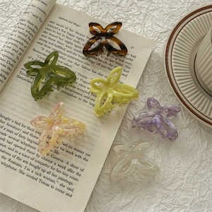 Chic acetate butterfly hair claws in various colors on an open book background