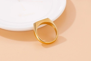 Detailed macro shot of the polished gold signet ring showcasing a flat oval top design