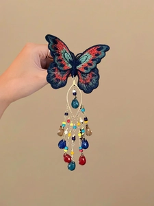 Détail de la pince à cheveux papillon brodée avec perles de cristal et pompons