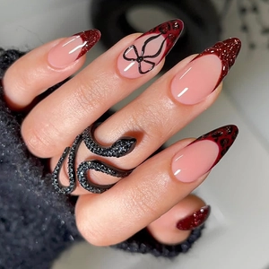 Detail of almond-shaped leopard print nails with 3D black bow and red glitter tips