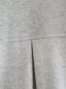 Macro detail of grey textured wool fabric with pleated stitching and horizontal seams
