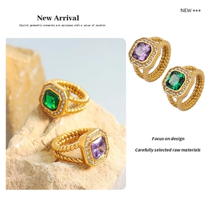 Macro detail of gold-plated twisted rings featuring emerald and amethyst square crystals
