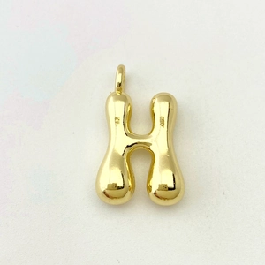 Macro shot of 3D balloon letter H pendant with polished gold surface and smooth edges