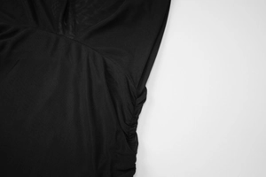 Detail view of black mesh fabric with elegant side pleats and ruched texture accents
