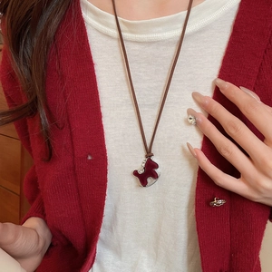 Close-up of a red enamel rocking horse pendant necklace with crystal accents on a model