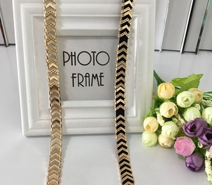 Detail of elegant gold V-shaped metal chain belts and black elastic waist belts