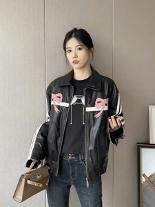 Détail de veste en cuir noir avec broderie nœud rose et rayures de sport blanches