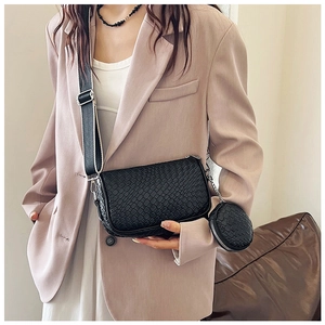 Detail of black woven texture shoulder bag with small round coin pouch on wide strap