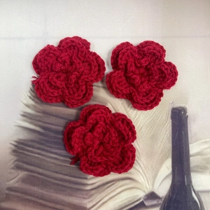 Detailed view of three red crochet flowers handcrafted for DIY clothing accessories