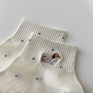 Nahaufnahme weißer Baumwollsocken mit feiner Hundestickerei und grauen Polka-Dots