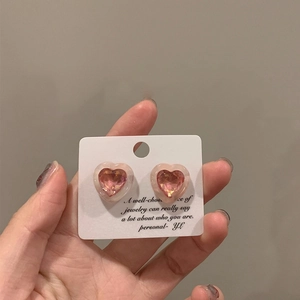 Detailed close-up of sweet pink heart-shaped crystal stud earrings on white display card